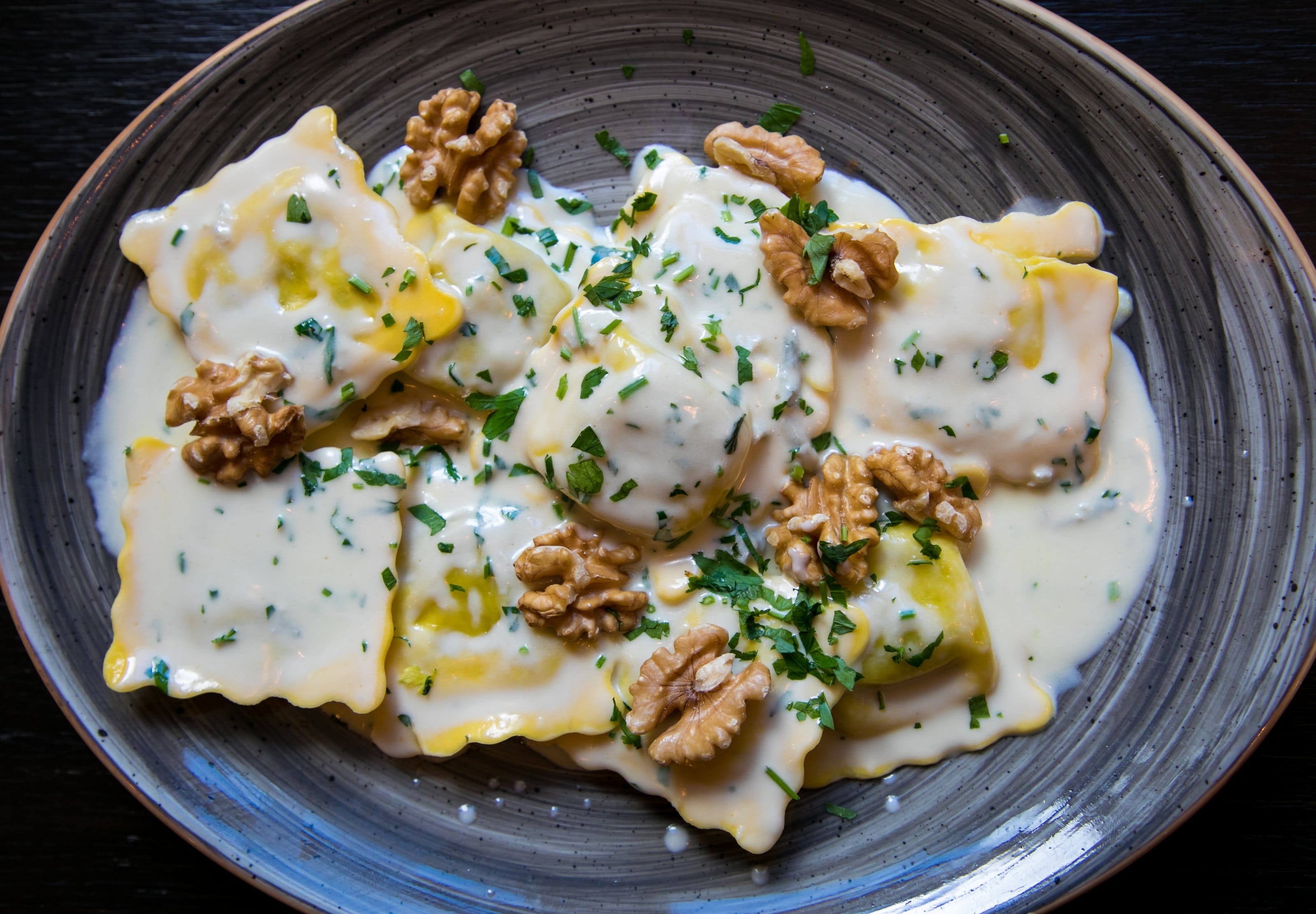 Ravioli with walnuts and herbs in a grey bowl